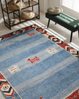 Willow Talia Blue Hand Knotted Wool Rug, a textured blue wool rug with a subtle, distressed pattern, lays flat on a light wood floor, inviting warmth and understated elegance into the room.