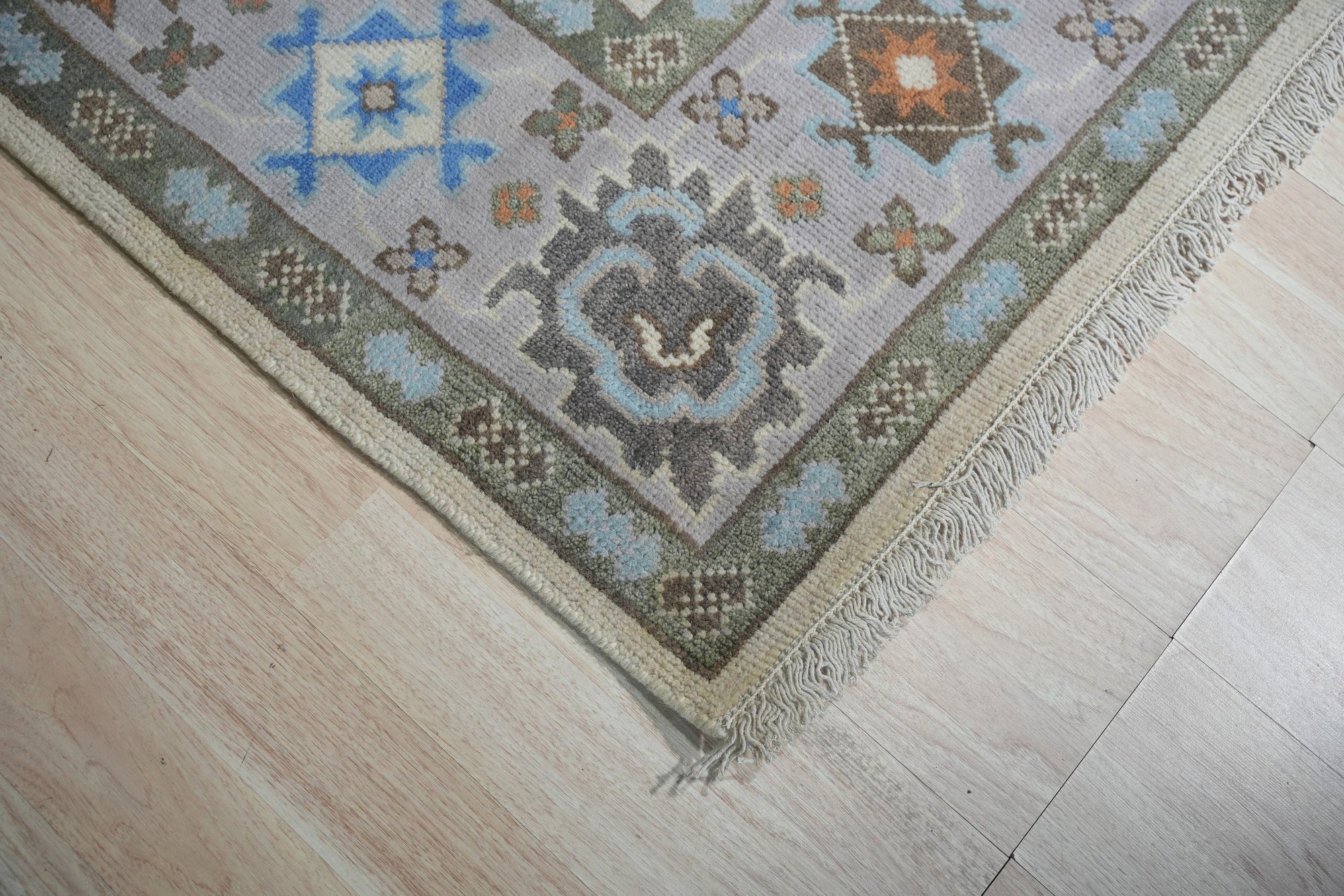 Enchanting Traditional Beige Hand Knotted Wool Rug, warm beige tones and intricate traditional patterns displayed in a room setting. Hand-knotted wool construction adds texture and depth to the rug's design.