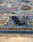 Tessa Laine Blue Hand Knotted Wool Rug, showcasing a geometric design with varying shades of blue and cream, seen in a bright, neutral room setting.