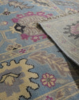 Tessa Laine Blue Hand Knotted Wool Rug, showcasing intricate patterns in varying shades of blue, laid in a bright, naturally lit room with modern furniture. Soft textures and hand-knotted construction visible.