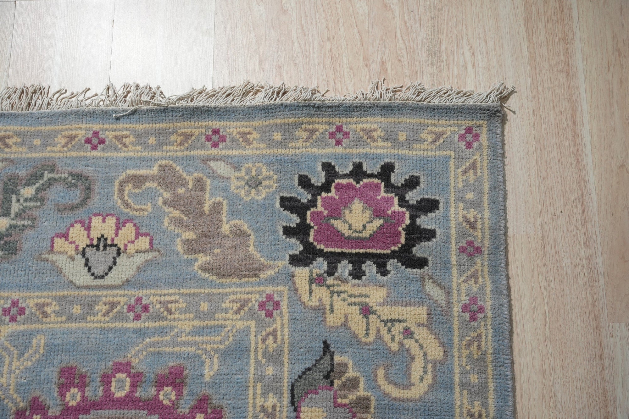 Tessa Laine Blue Hand Knotted Wool Rug, showcasing a modern geometric pattern with varying shades of blue, cream, and gray, laid on a light hardwood floor.