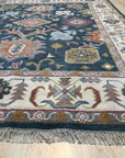 Sarrah Oushak Charcoal Hand Knotted Wool Rug, charcoal wool rug with a traditional Oushak design, seen in a bright, modern living room setting with light wood floors and neutral furniture.