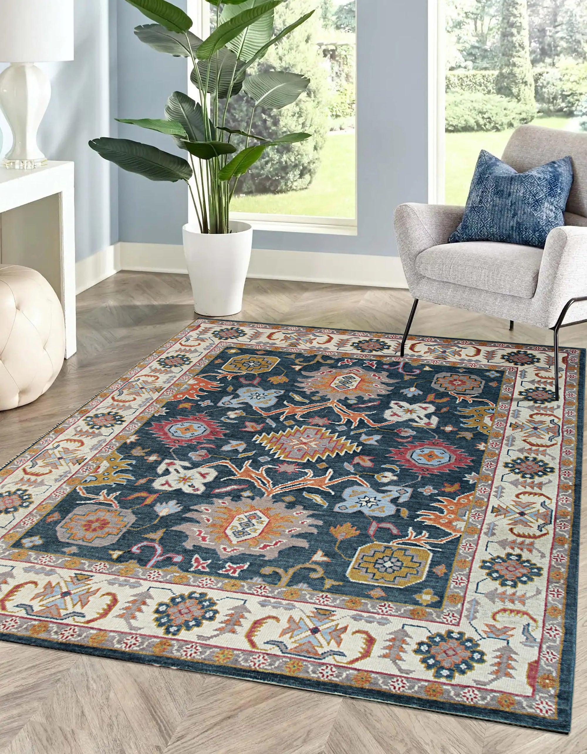 Sarrah Oushak Charcoal Hand Knotted Wool Rug, displaying intricate floral patterns in charcoal gray wool, complements a light, minimalist living space with a natural wood coffee table and bright, airy daylight.