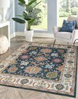 Sarrah Oushak Charcoal Hand Knotted Wool Rug, displaying intricate floral patterns in charcoal gray wool, complements a light, minimalist living space with a natural wood coffee table and bright, airy daylight.
