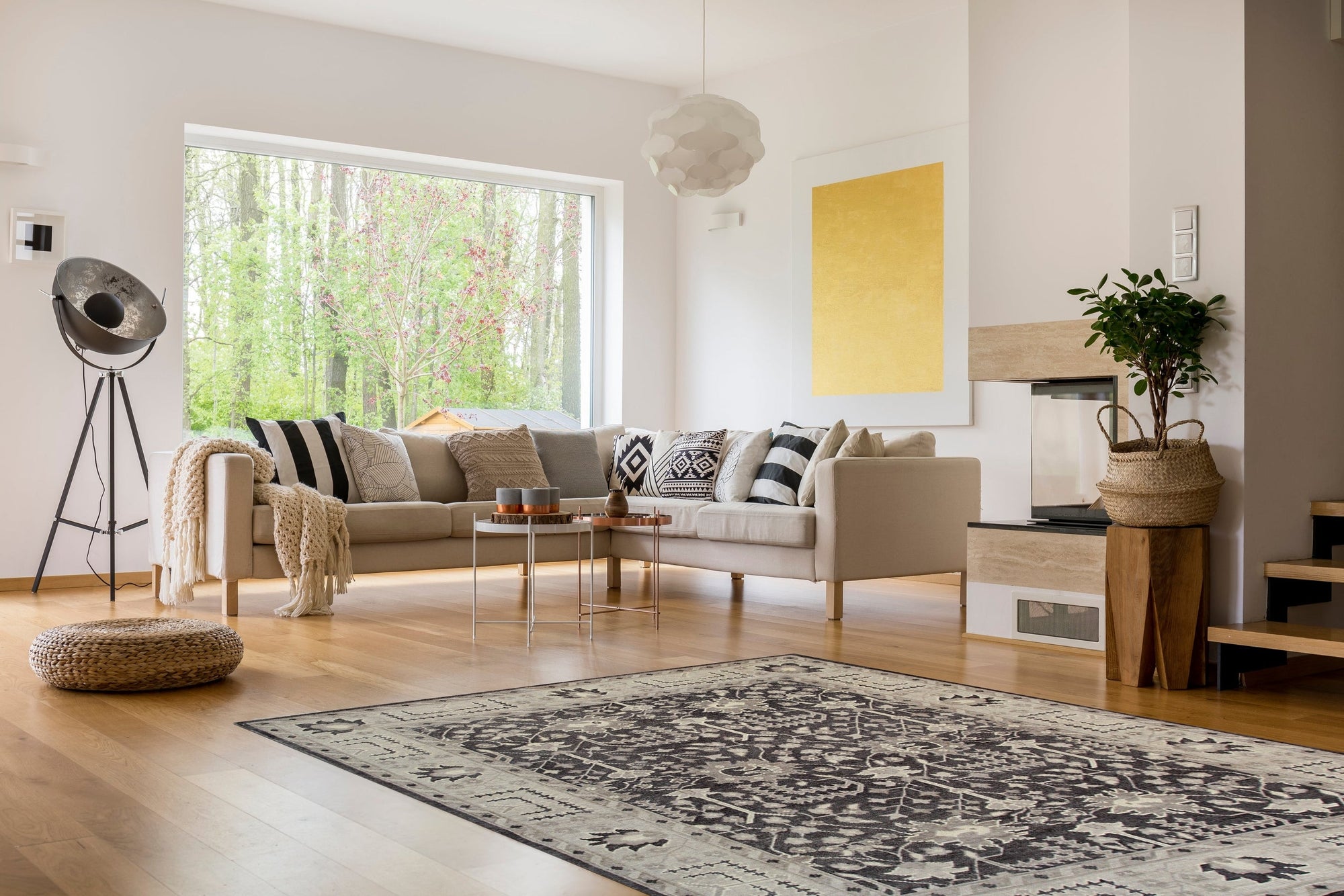 Cozy Oushak Charcoal Hand Knotted Wool Rug, a charcoal wool rug with a traditional Oushak design, seen in a bright, modern living room setting, partially underneath a light-colored sofa and coffee table.