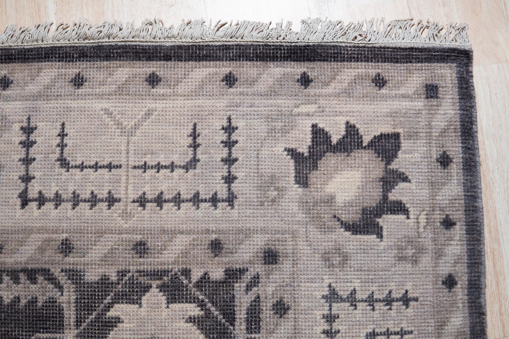 Cozy Oushak Charcoal Hand Knotted Wool Rug, its textured charcoal wool pile and intricate Oushak pattern grounding a bright living space; natural light highlights the rug's hand-knotted construction.
