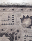 Cozy Oushak Charcoal Hand Knotted Wool Rug, its textured charcoal wool pile and intricate Oushak pattern grounding a bright living space; natural light highlights the rug's hand-knotted construction.