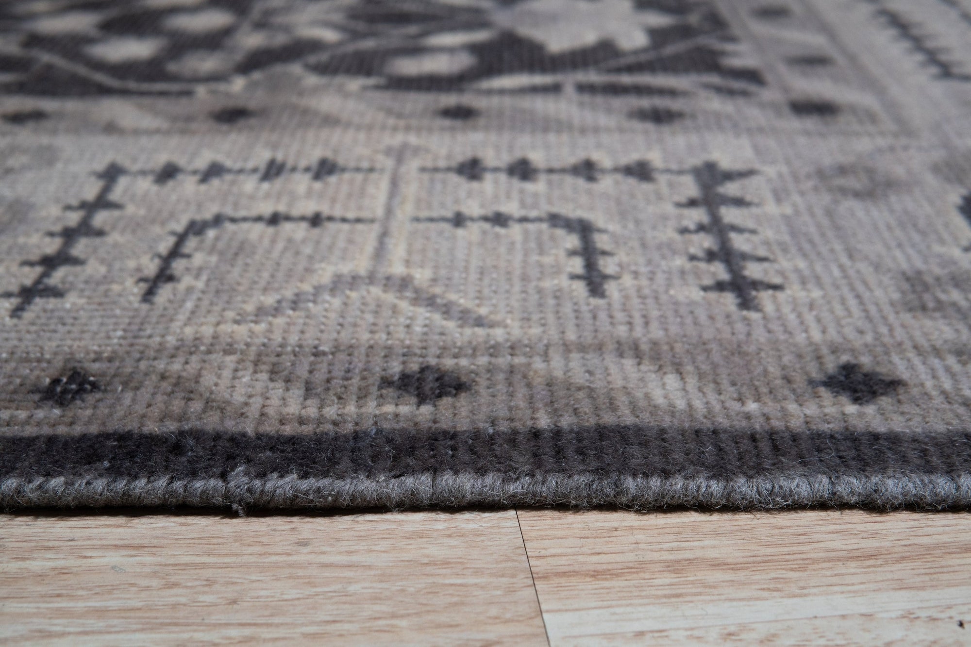 Cozy Oushak Charcoal Hand Knotted Wool Rug displayed in a living room setting, its charcoal hues grounding a space with neutral furniture and natural light, showcasing the rug's intricate hand-knotted detail and warm, inviting texture.