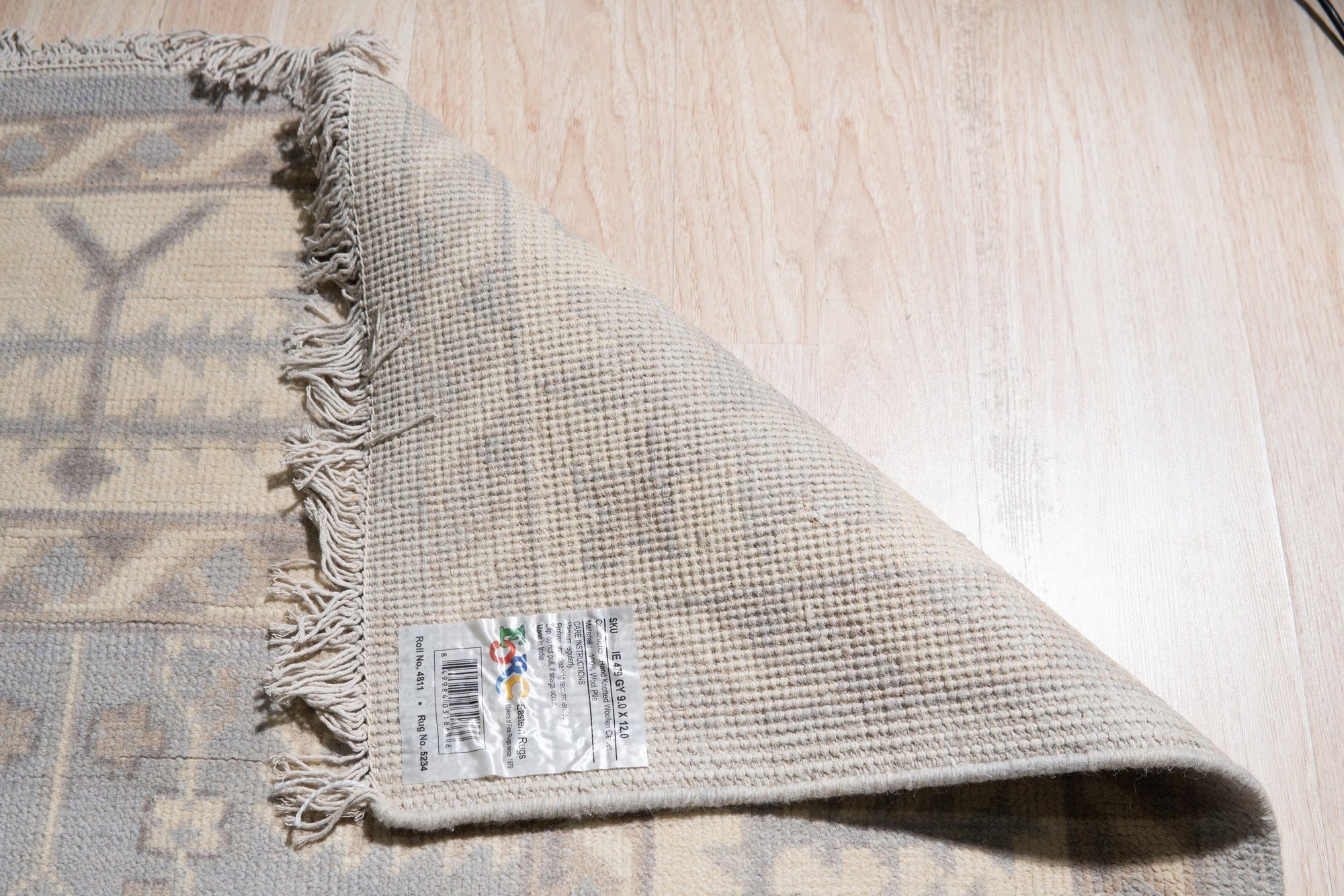 Harlow Traditional Gray Hand Knotted Wool Rug, its intricate pattern unfolding in cool grays, anchors a bright living space. Sunlight illuminates the rug's dense, hand-knotted wool texture.