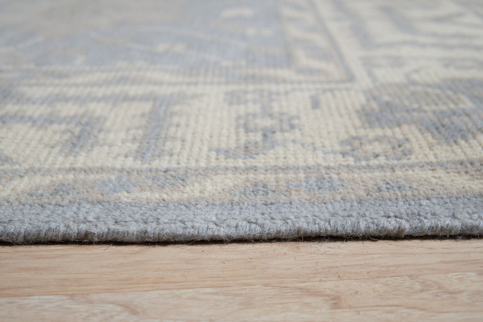 Selene Oushak Rust Hand Knotted Wool Rug graces a warmly lit living space, its intricate floral patterns and rich rust hues anchoring the room. Hand-knotted wool construction evident in the soft texture and subtle variations, lending an air of timeless elegance to the scene.