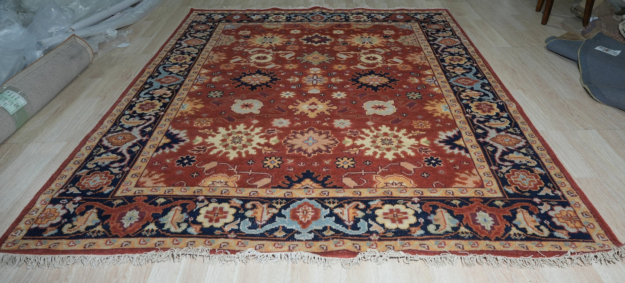 Majestic Versatile Red Hand Knotted Wool Rug, seen filling a sun-drenched living room, its vibrant red wool a warm counterpoint to the cool-toned walls and modern furniture. The hand-knotted construction is evident in the intricate patterns that draw the eye.