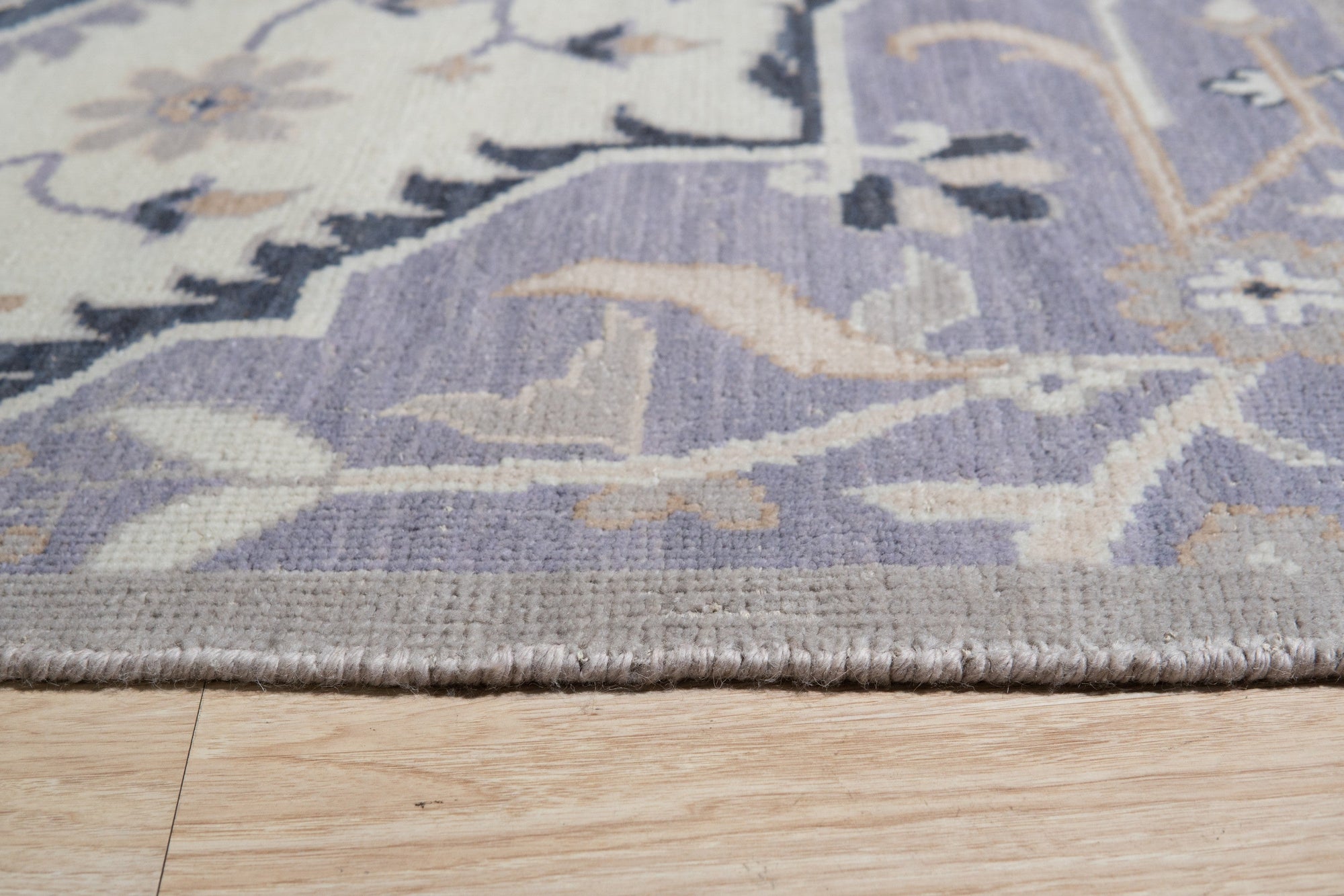 Timeless Oriental Ivory Hand Knotted Wool Rug, showcasing intricate floral patterns and geometric borders in soft ivory tones, lying flat on a light surface emphasizing the handcrafted detail.