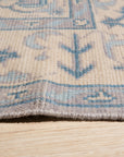 Iris Bianca Gray Hand Knotted Wool Rug, displaying subtle textural variations and a soft, muted gray palette, rests elegantly on a light wood floor. Delicate details and hand-knotted construction are visible in the close-up shot.