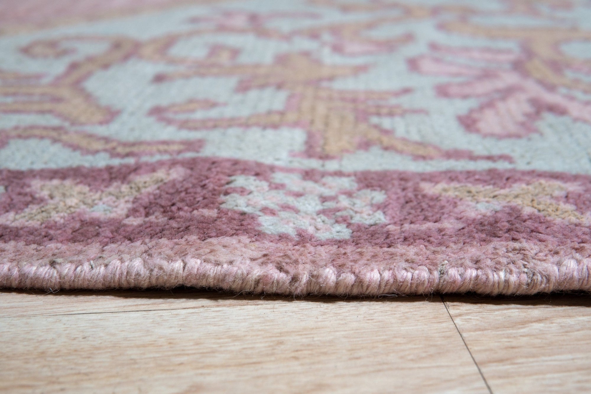 Lydia Oriental Pink Hand Knotted Wool Rug, showcasing intricate floral patterns woven in shades of pink and cream, softens a well-lit living space.
