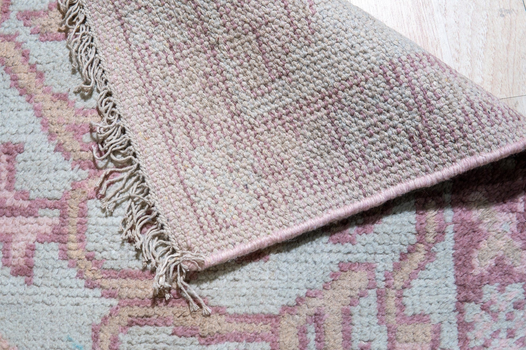 Lydia Oriental Pink Hand Knotted Wool Rug, a plush wool rug with intricate floral patterns in varying shades of pink, cream, and muted blues, lays centered on a light hardwood floor, providing a soft, luxurious accent to the room's interior.
