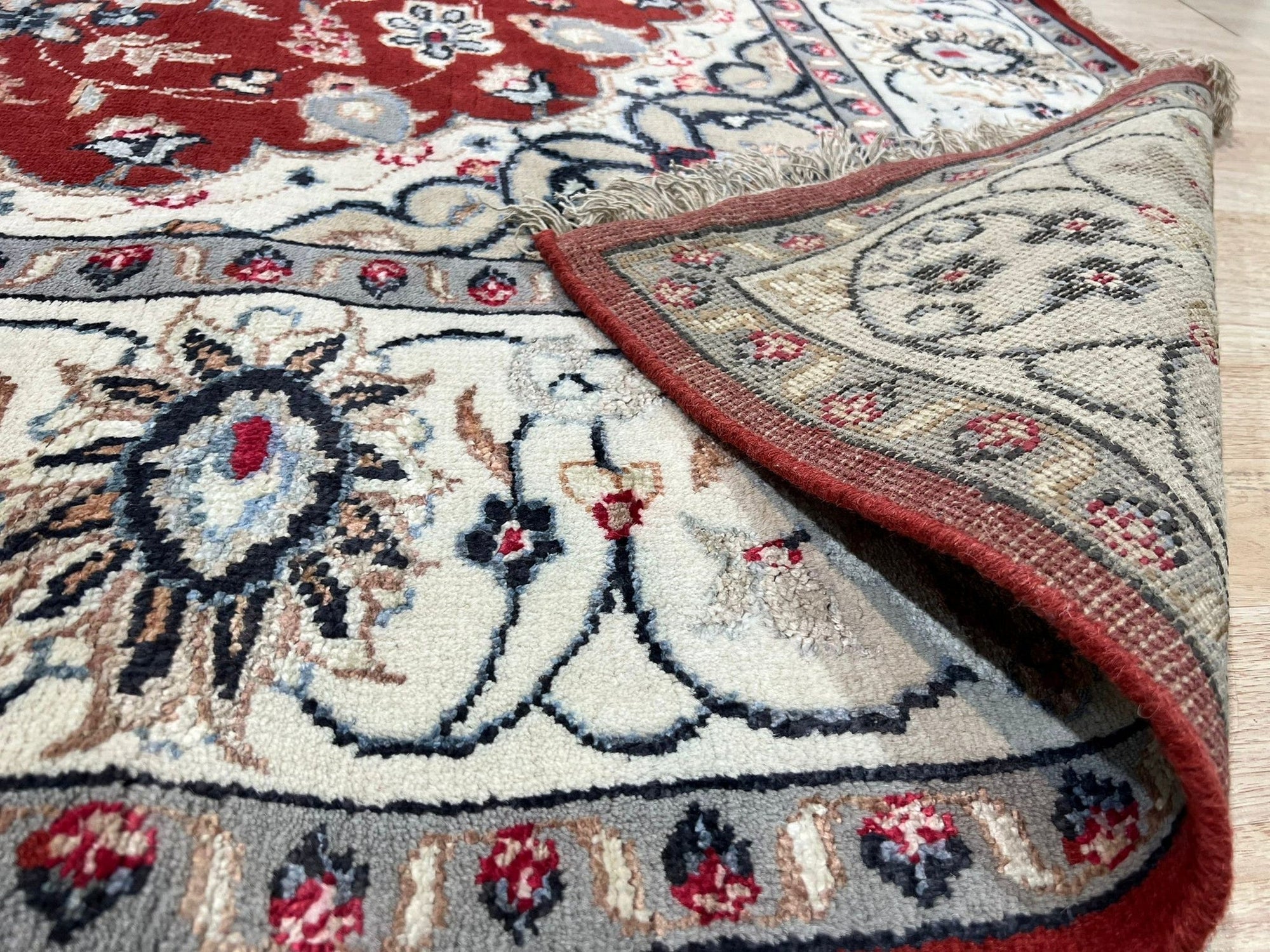 Selene Trara Red Hand Knotted Wool & Silk Rug, featuring intricate patterns in vibrant reds and subtle neutrals, graces a softly lit interior space.