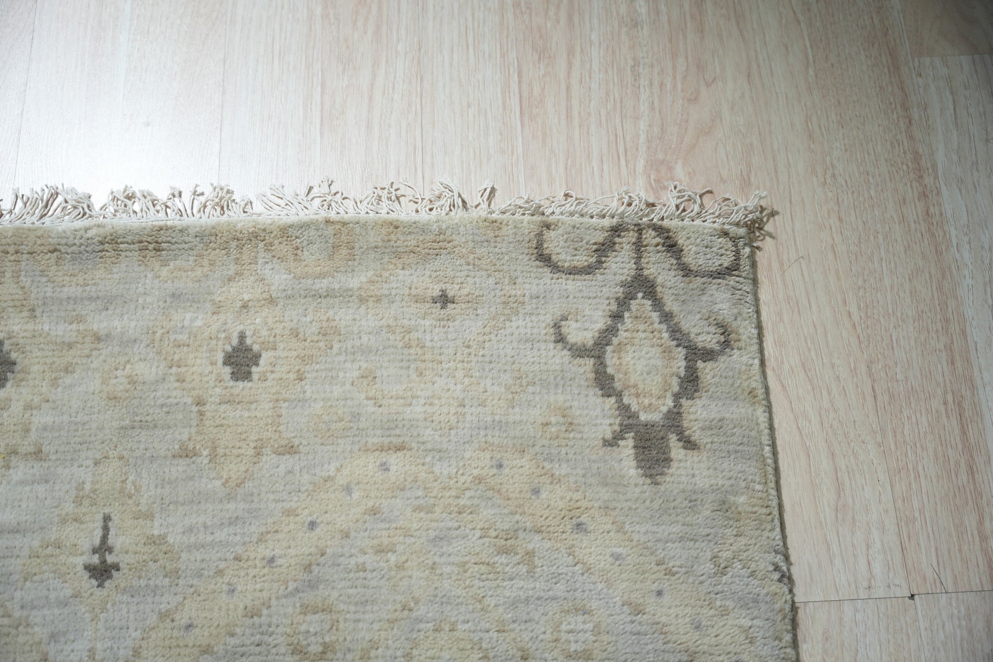 Lush Traditional Gray Hand Knotted Wool Rug, its intricate floral and geometric patterns unfolding across a soft gray field, rests subtly in a warmly lit room with hardwood flooring.