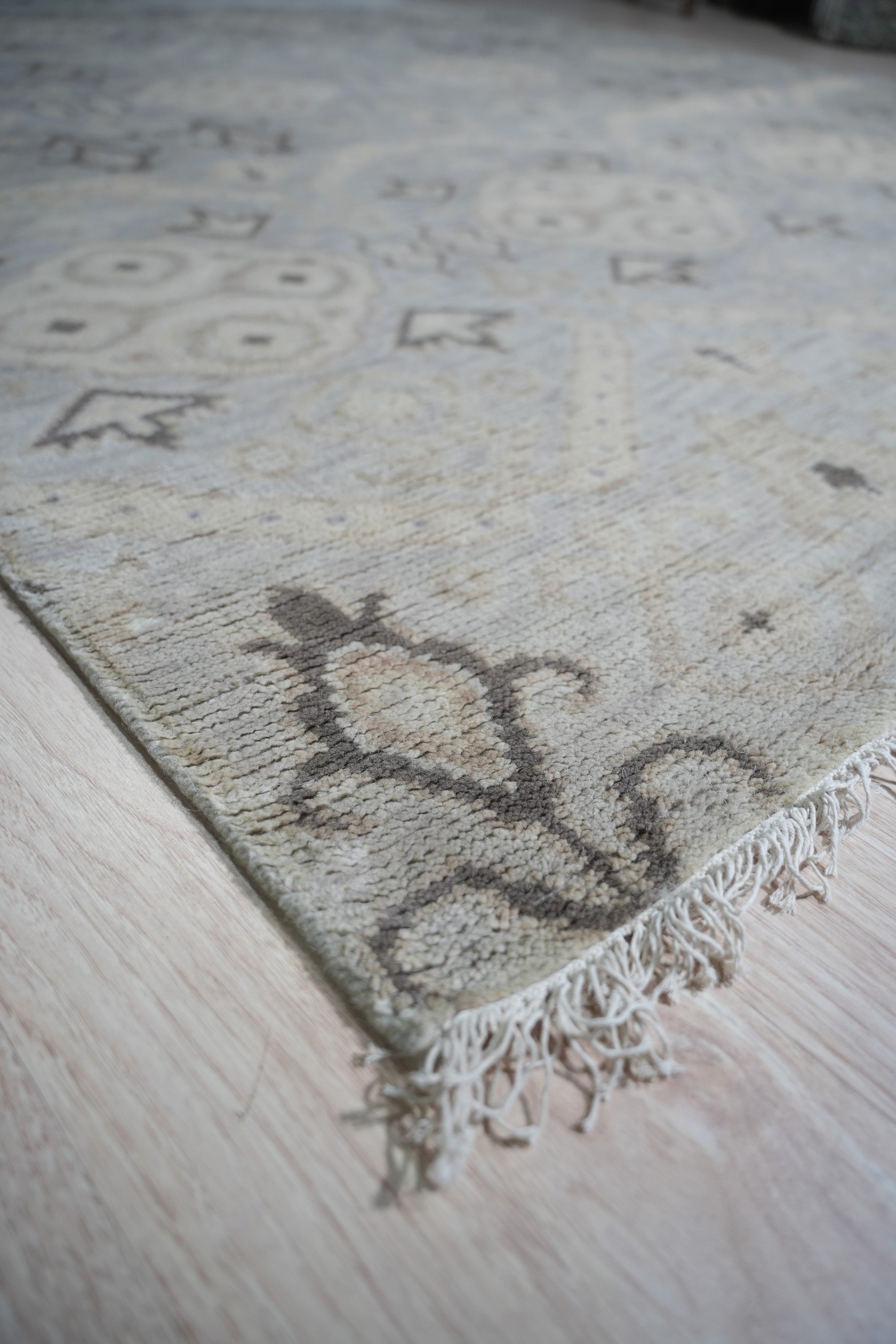 Lush Traditional Gray Hand Knotted Wool Rug, its intricate pattern unfurling in shades of gray and cream, sits anchored in a light-filled living room, offering a soft, woolen foundation to the minimalist space.