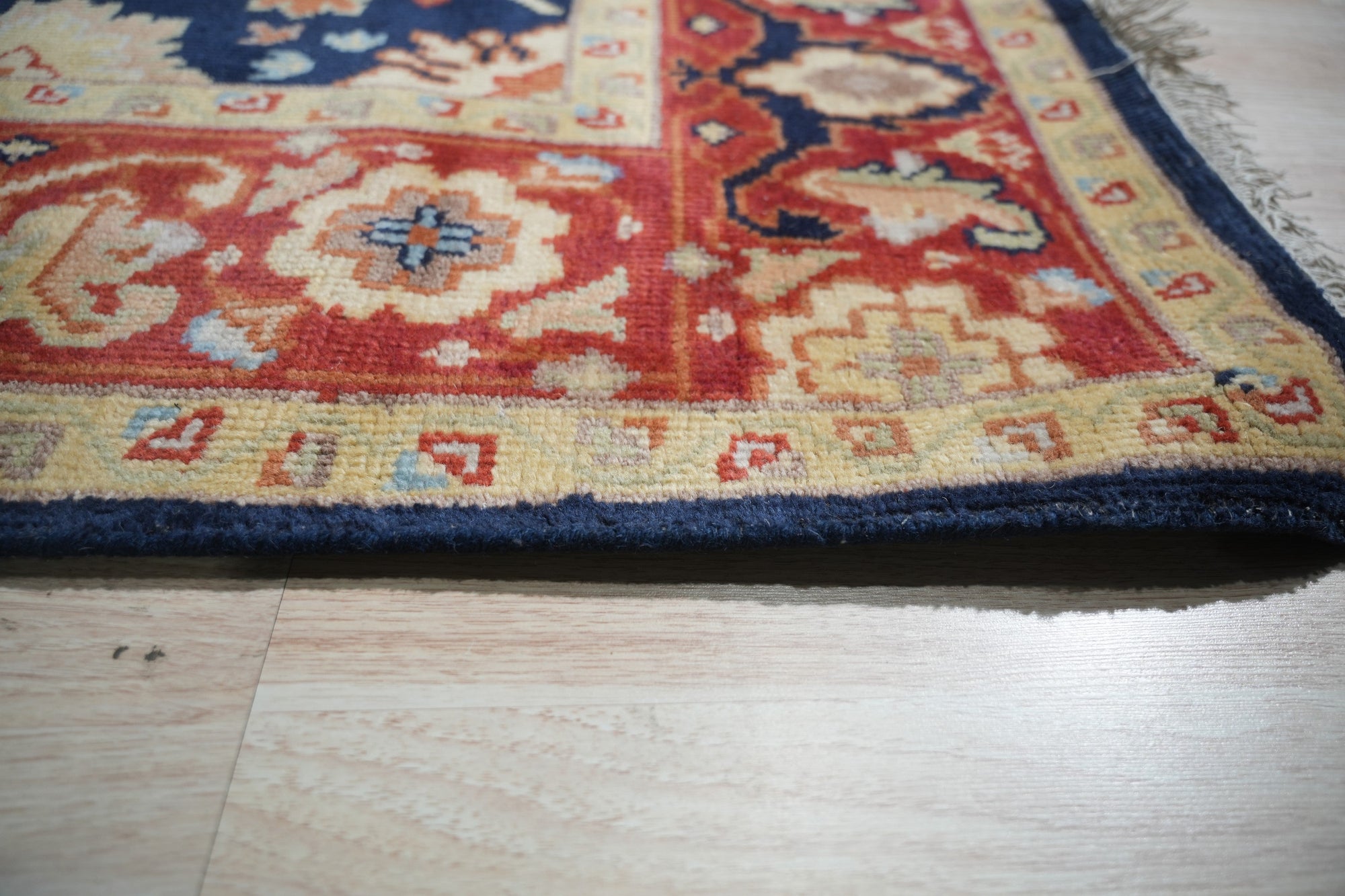 Chloe Amara Navy Hand Knotted Wool Rug, its intricate pattern and rich navy hues lending sophistication to a warmly lit living space.