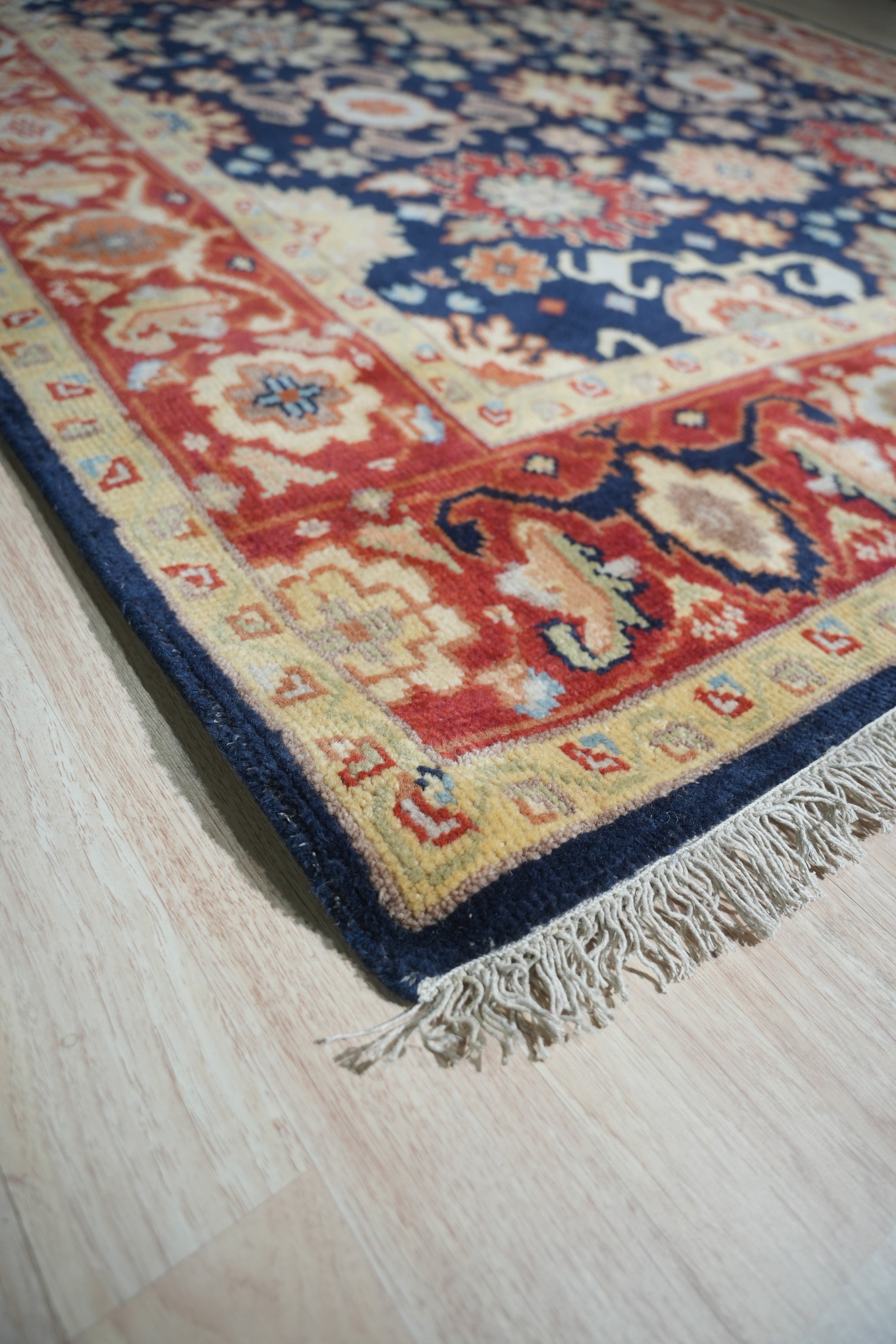 Chloe Amara Navy Hand Knotted Wool Rug, displaying intricate patterns in deep navy and subtle cream hues, lays gracefully in a brightly lit living room setting.