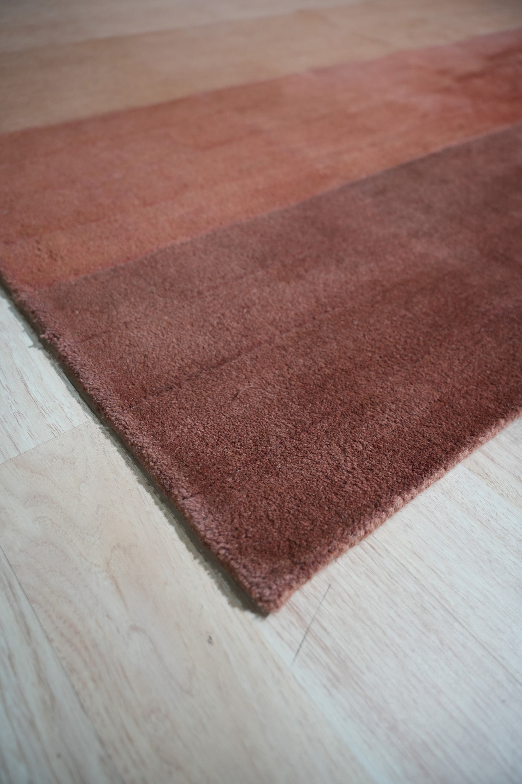 Isla Striped Rust Hand Tufted Wool Rug, warm rust tones and earthy stripes define this hand-tufted wool rug, grounding a bright living space with textural depth and visual interest.