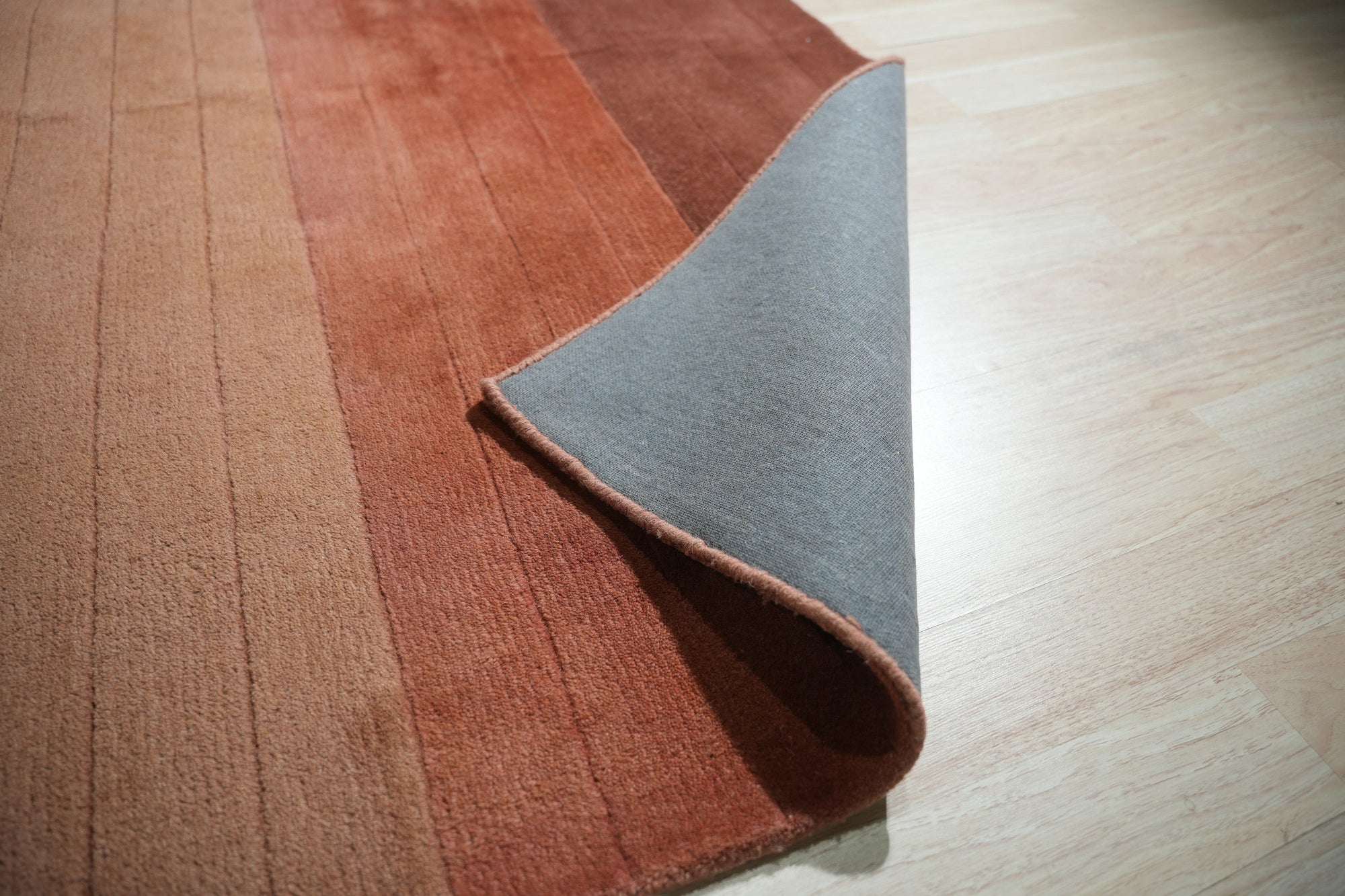 Isla Striped Rust Hand Tufted Wool Rug, its warm rust hues and textured wool stripes creating a cozy, inviting ambiance in a naturally lit living space with neutral furniture.