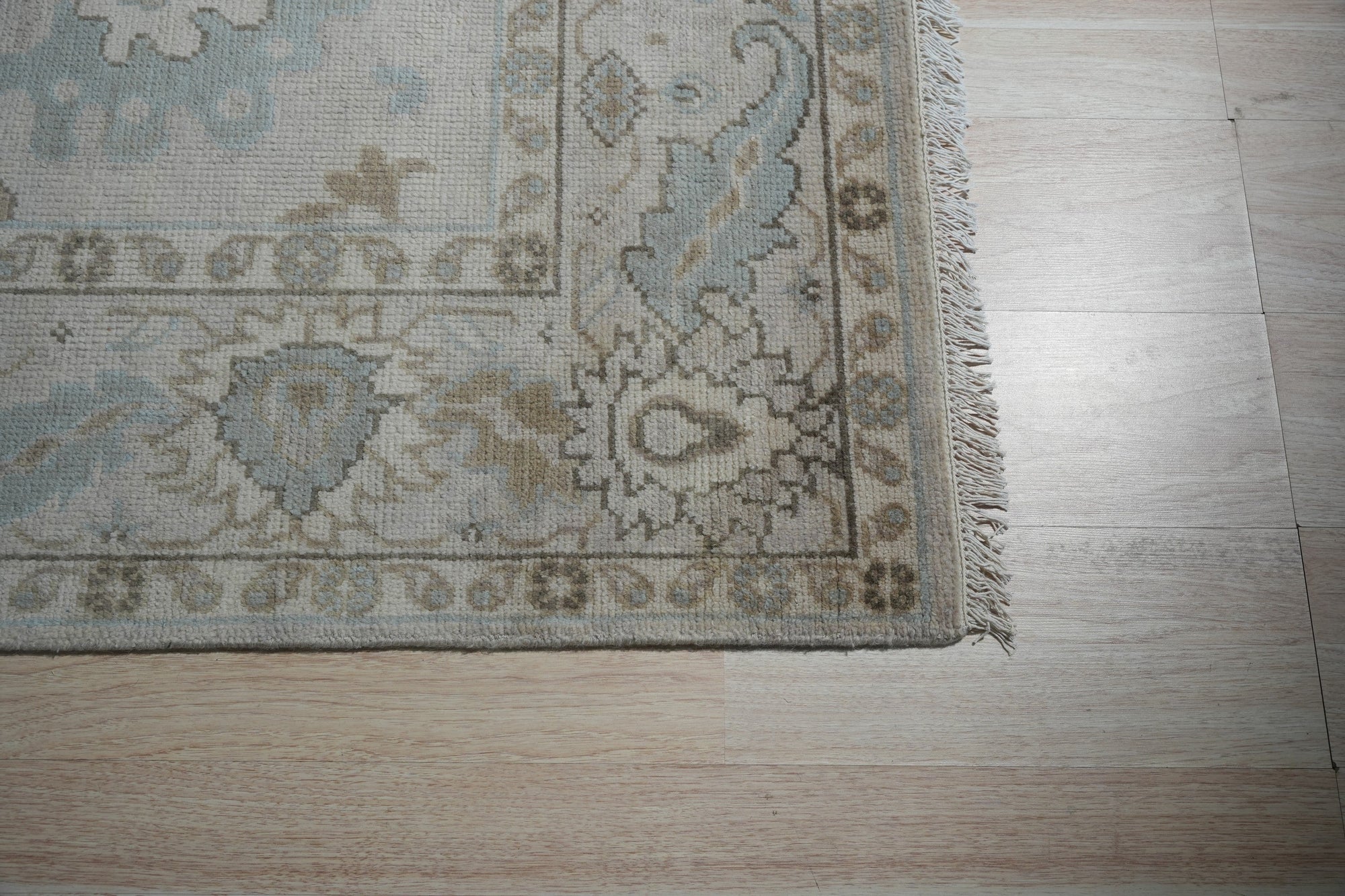 Classic Tessa Beige Nan Rug, a subtle, textured rug with a low pile construction, displayed in a warmly lit interior setting with contemporary furniture.