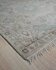 Classic Tessa Beige Nan Rug, its intricate geometric pattern rendered in soft beige tones, lying elegantly on a light wood floor, suggesting a warm and inviting atmosphere.