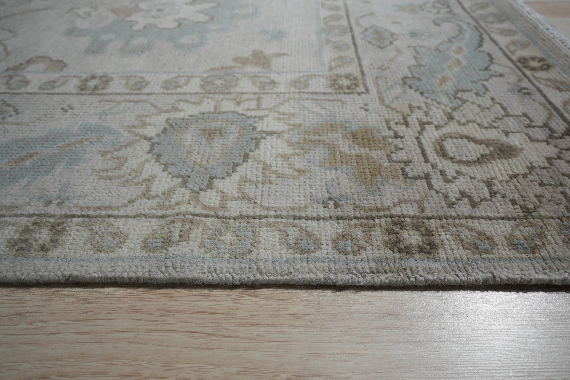 Classic Tessa Beige Nan Rug, a neutral beige rug with a subtle, geometric Nan design, showcased in a well-lit living room setting with contemporary furniture and ample natural light.