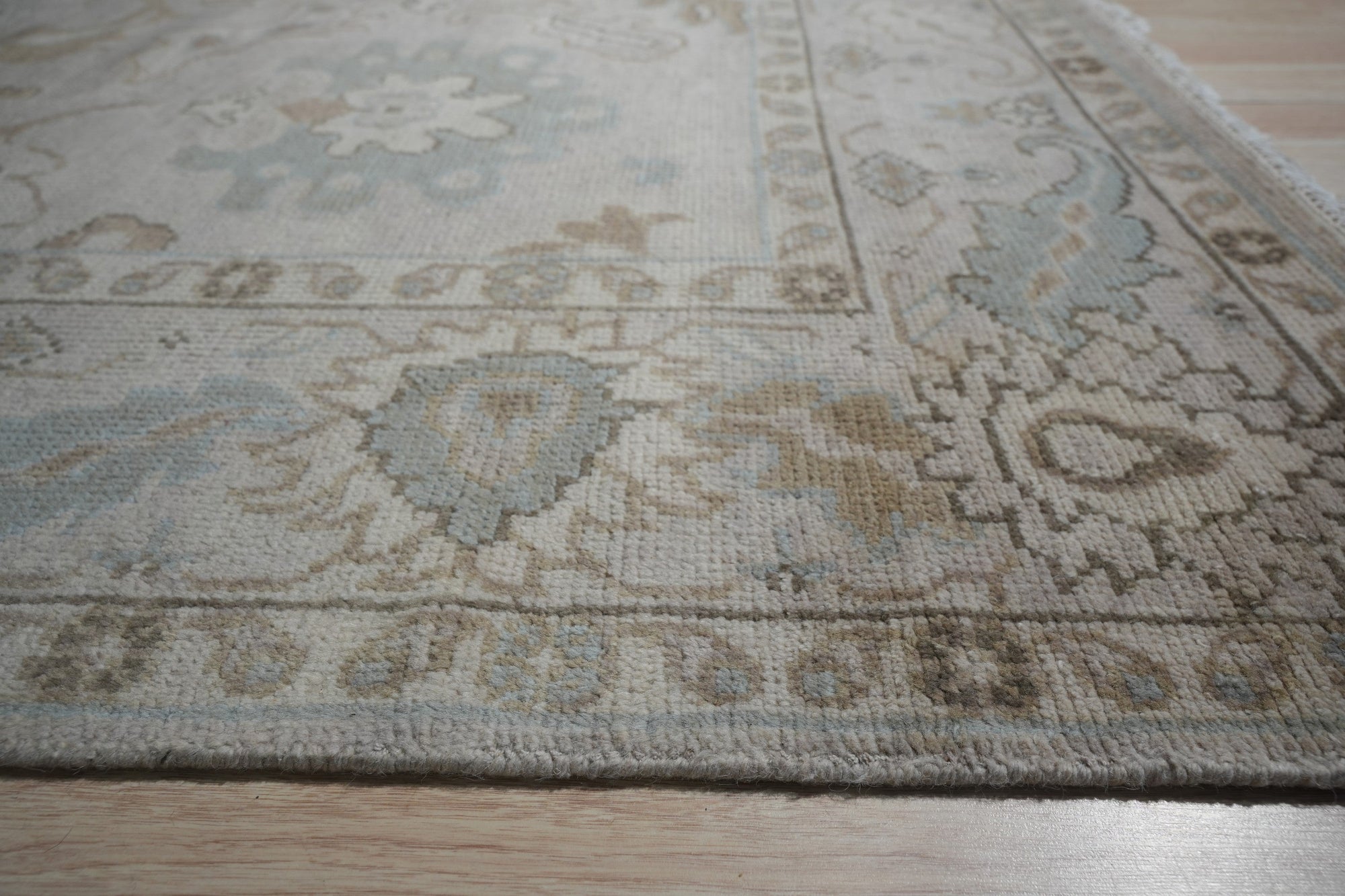 Classic Tessa Beige Nan Rug graces a warmly lit living room; soft beige hues and subtle, geometric patterns unfold across its woven surface, anchoring a comfortable seating area.