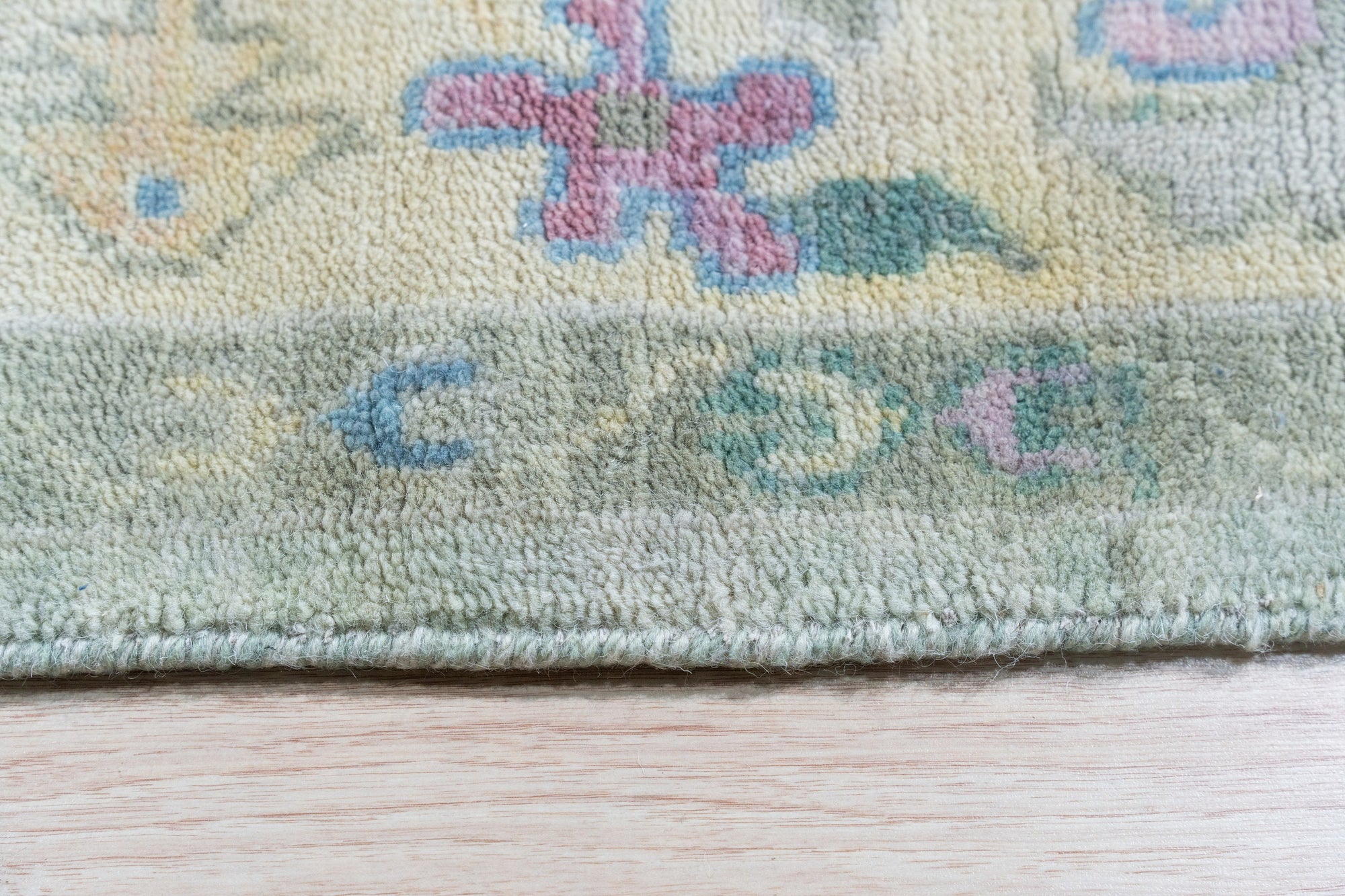 Elegant Timeless Light Green Hand-Knotted Wool Rug, with a subtle, traditional pattern, displayed in a bright living room setting with natural light highlighting the rug's soft green tones and plush wool texture.