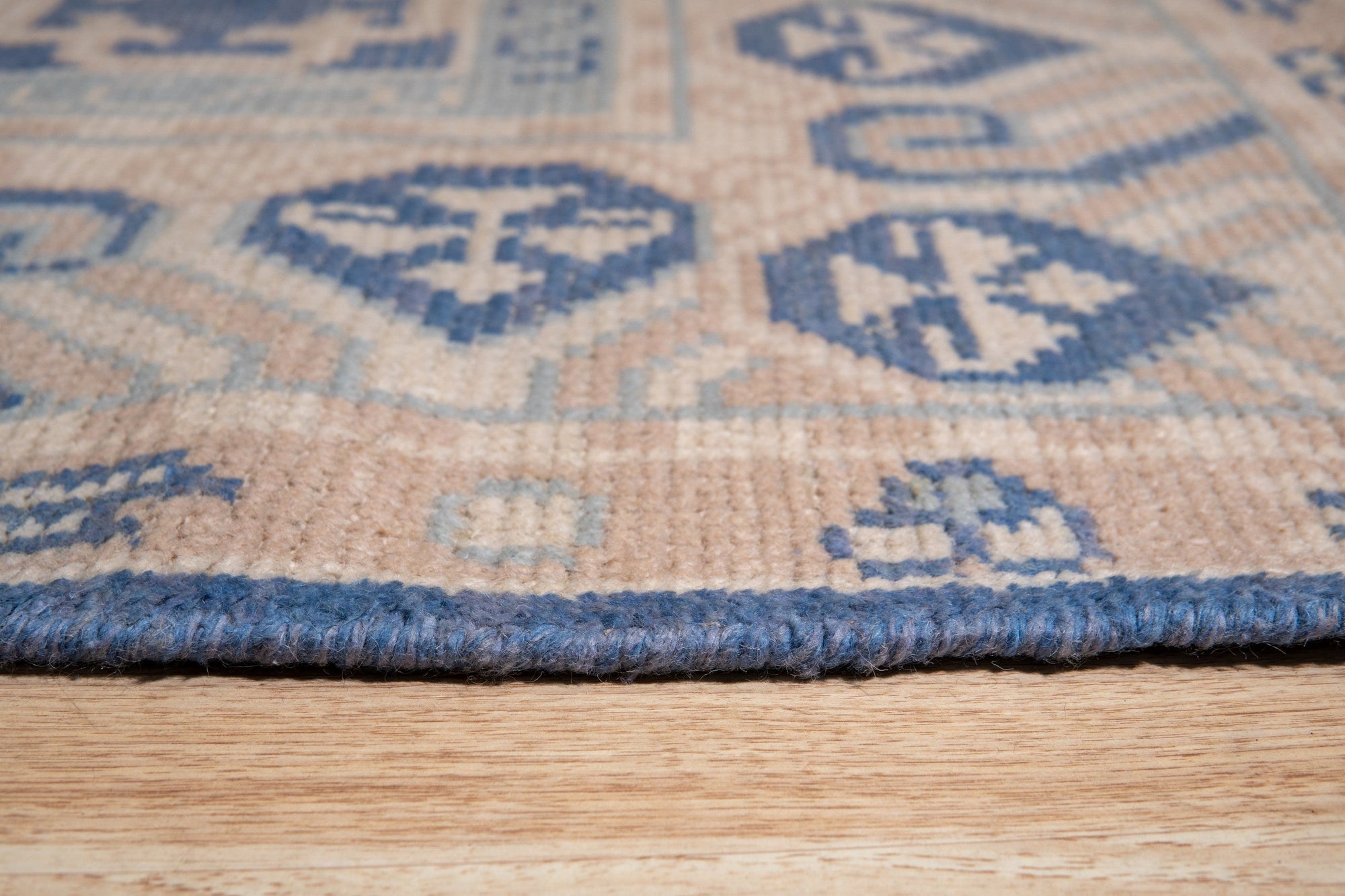 Bespoke Oriental Blue Hand Knotted Wool Rug, its intricate floral pattern in shades of blue and cream unfolds across a living room setting, demonstrating its scale and presence on a dark wood floor.