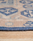 Bespoke Oriental Blue Hand Knotted Wool Rug, its intricate floral pattern in shades of blue and cream unfolds across a living room setting, demonstrating its scale and presence on a dark wood floor.