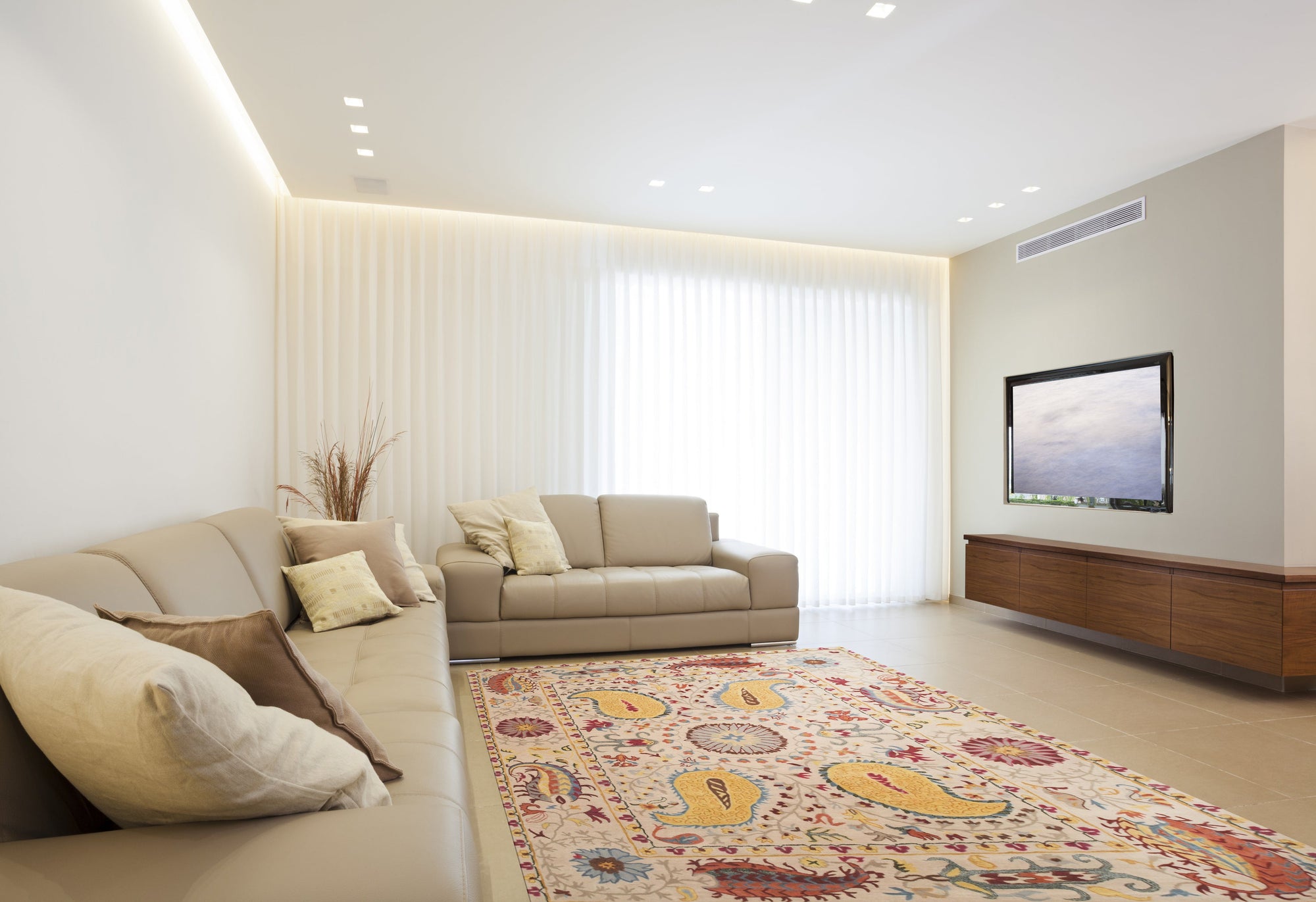 Chic Delicate Ivory Hand Tufted Wool Rug, seen under a modern grey sofa with patterned throw pillows, its soft ivory pile adding warmth and texture to the living room space.