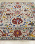 Ruby Fiona Ivory Hand Tufted Wool Rug, seen in a well-lit room, features a subtle, textured pattern in creamy ivory. Hand-tufted wool construction provides a soft, inviting surface.