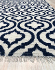 Trendy Moroccan Navy Hand Knotted Wool Rug, its intricate geometric pattern in navy and cream tones anchoring a bright, airy living room setting.