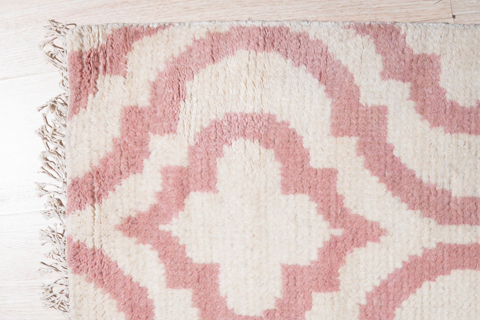 Inviting Moroccan Pink Hand Knotted Wool Rug, a soft pink wool rug with a geometric diamond pattern, seen in a bright, airy living space.