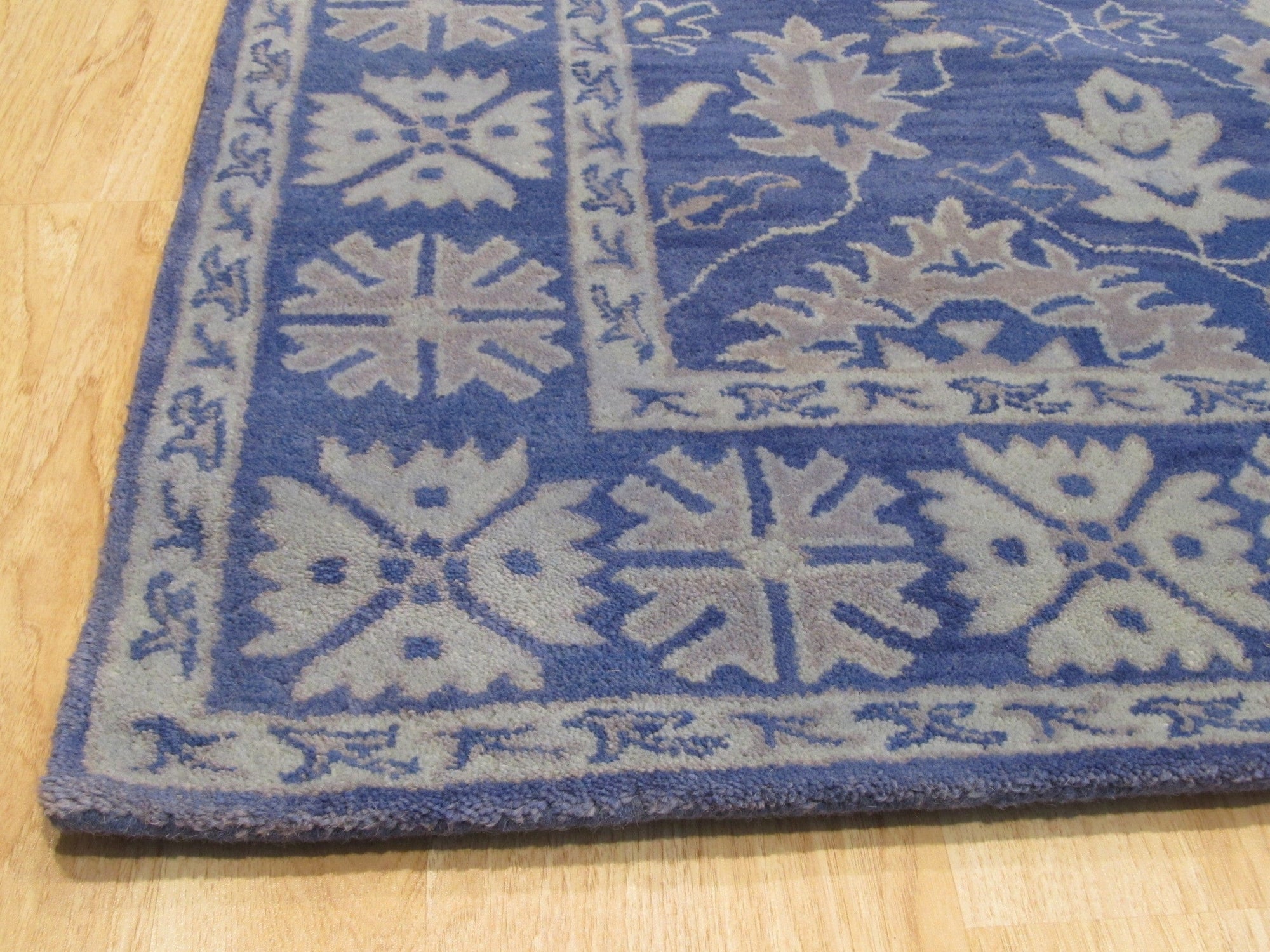 Rustic Oriental Blue Hand Tufted Wool Rug, its intricate, hand-tufted patterns swirling in shades of blue, bringing an antique-inspired elegance to the room.