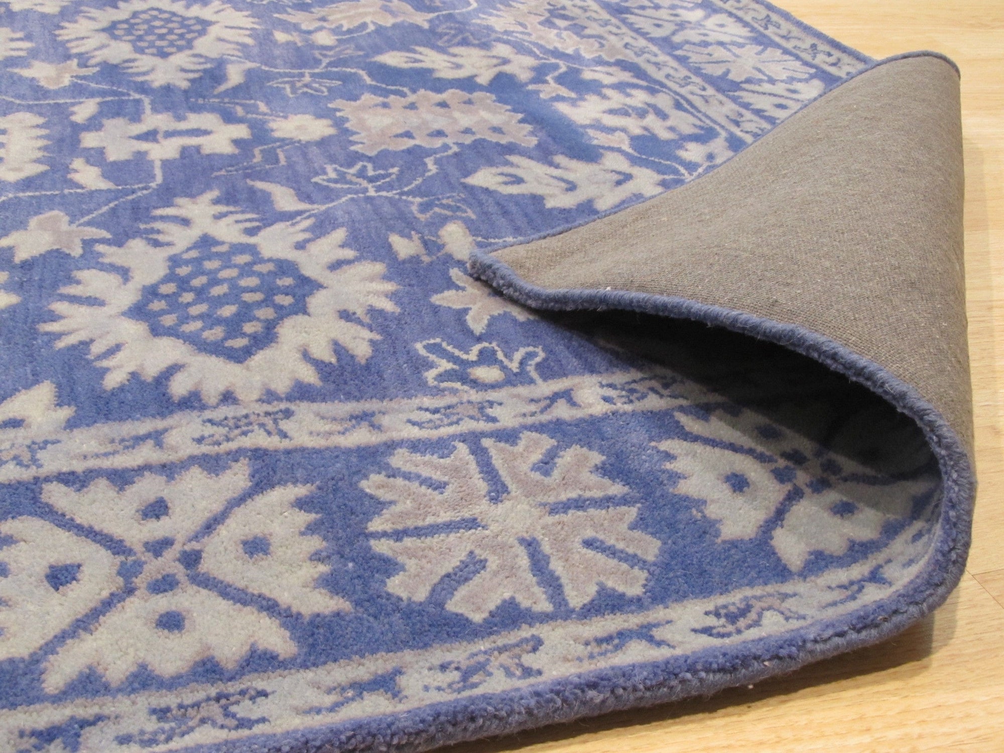 Rustic Oriental Blue Hand Tufted Wool Rug, showcasing its intricate, hand-tufted construction, blends deep blues and earthy tones in a distressed oriental pattern, lending a timeless, rustic charm to the room.