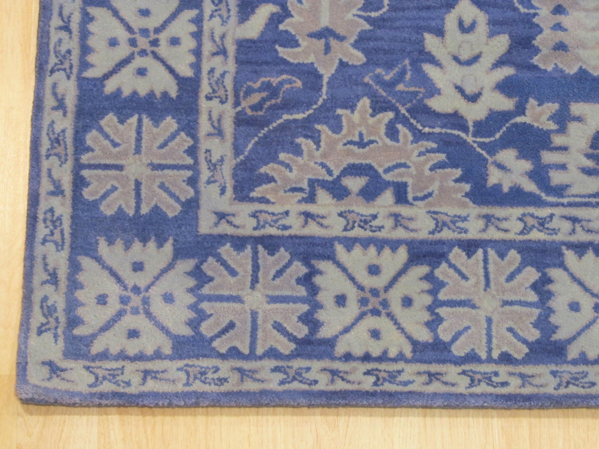 Rustic Oriental Blue Hand Tufted Wool Rug, displaying its intricate patterns and rich blues amidst warm, neutral tones in a living room setting.