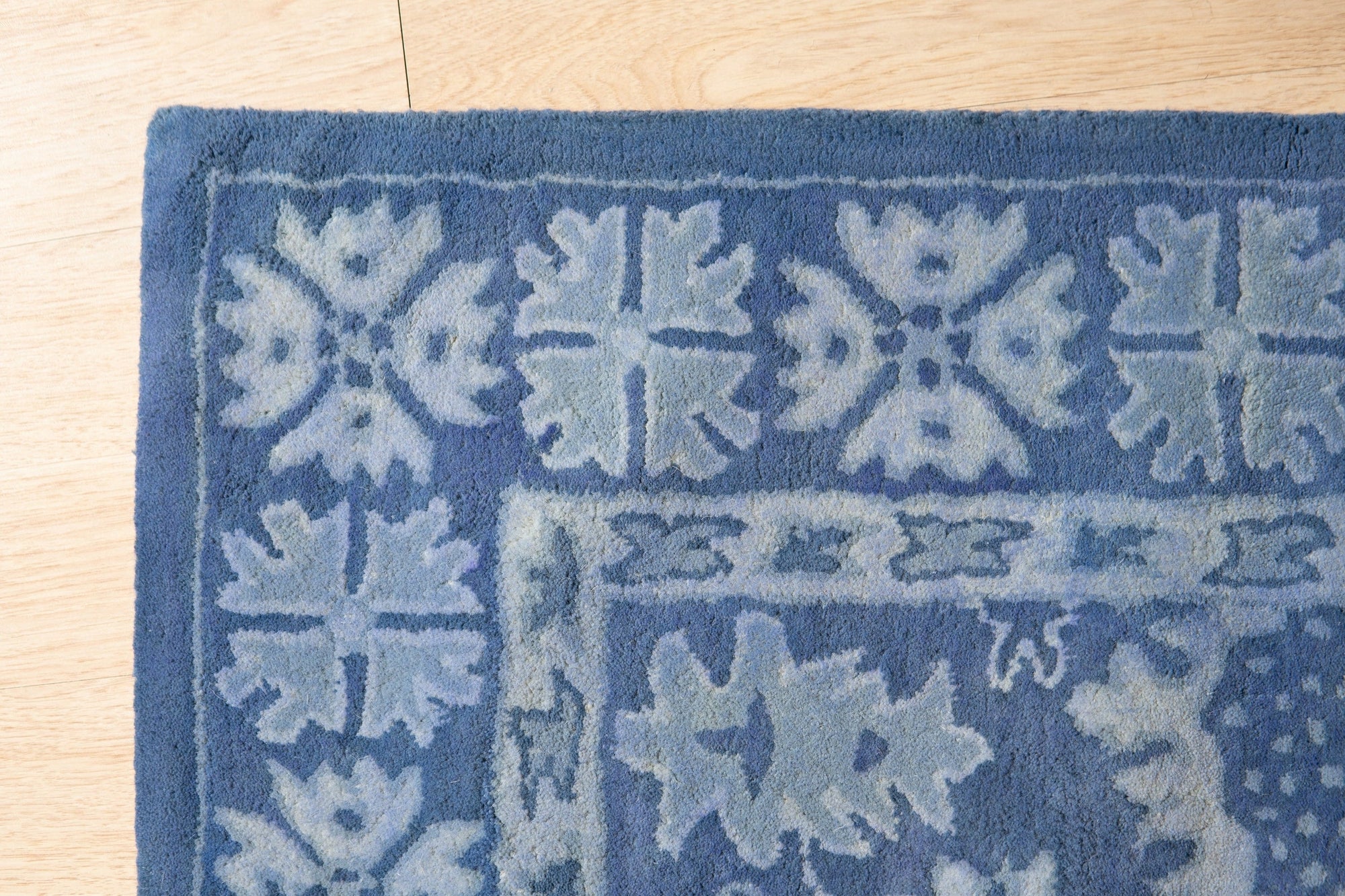Rustic Oriental Blue Hand Tufted Wool Rug, showcasing intricate patterns and deep blue hues, nestled within a warmly lit room, creating a sense of classic comfort.