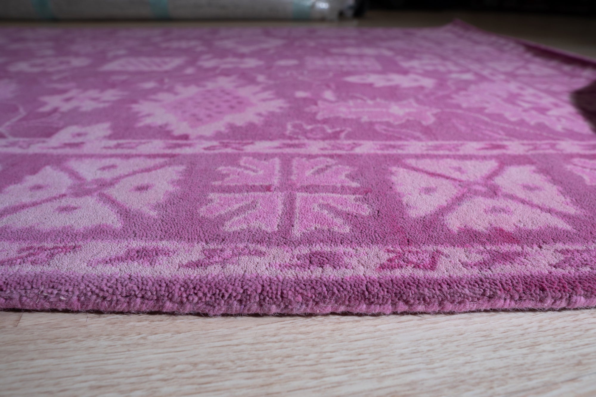 Opulent Oriental Pink Hand Tufted Wool Rug, showcasing a detailed floral pattern in shades of pink and cream, seen in a bright, neutral room setting.