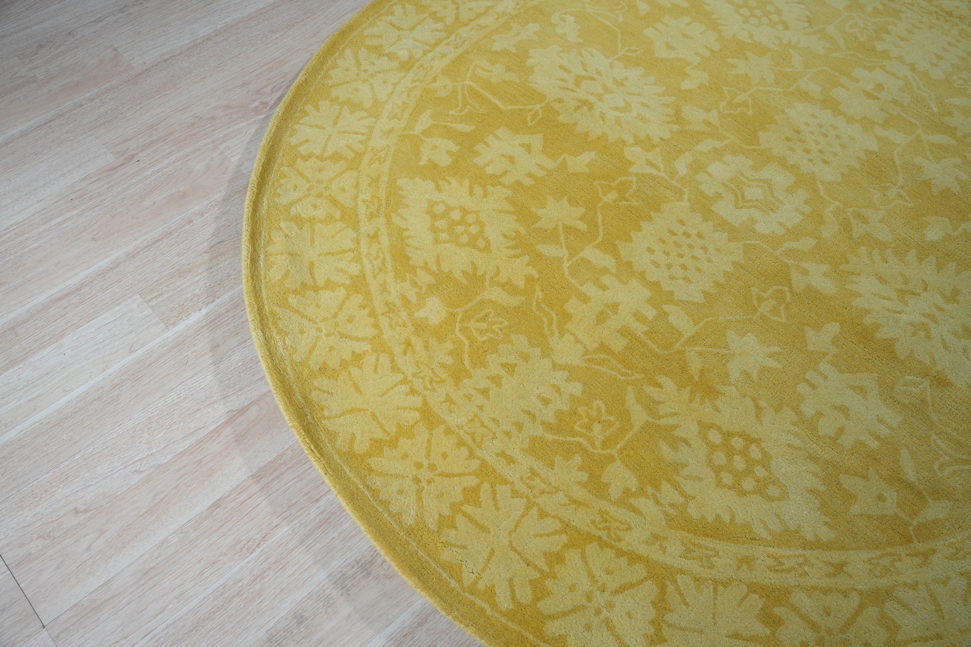 Comfortable Oriental Yellow Hand Tufted Wool Rug, its golden hues and intricate oriental design radiating warmth on a light wood floor.