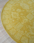 Comfortable Oriental Yellow Hand Tufted Wool Rug, its golden hues and intricate oriental design radiating warmth on a light wood floor.