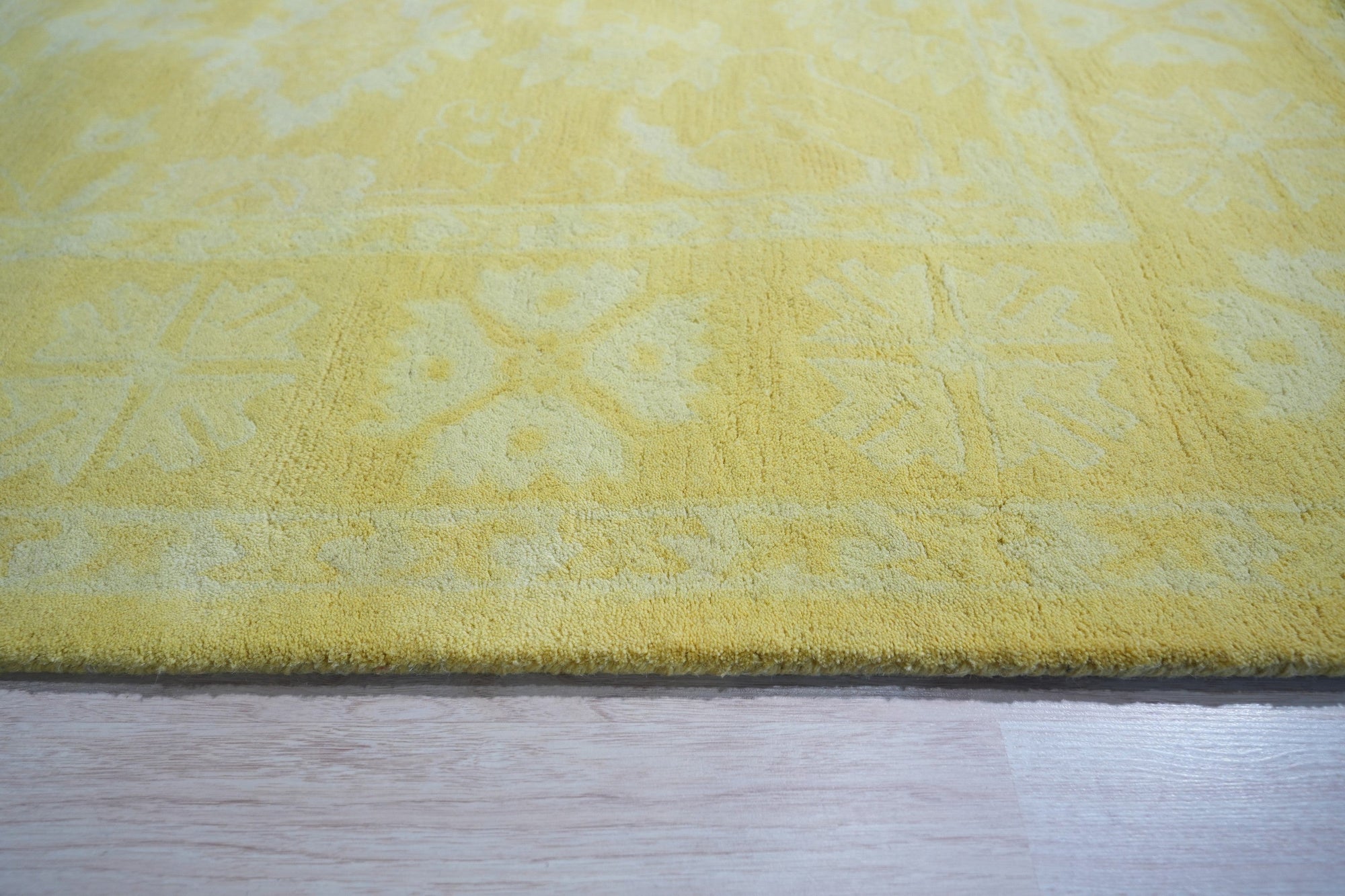 Comfortable Oriental Yellow Hand Tufted Wool Rug, warm golden hues and intricate floral patterns unfurl across this hand-tufted wool rug, its luxurious texture adding comfort and sophistication to a brightly lit living space.