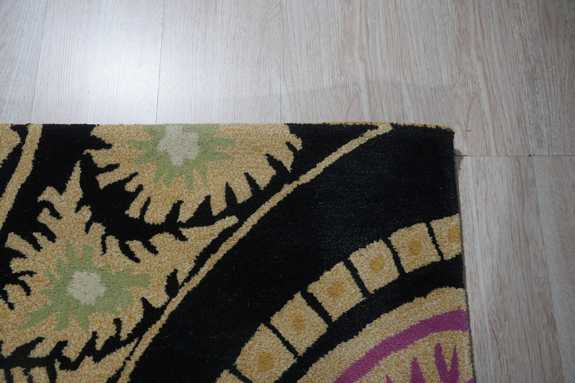 Opulent Nina Black Hand Tufted Wool Rug, a luxurious accent with its deep black wool and intricate hand-tufted texture, positioned as a decorative element within a bright, modern living room space.