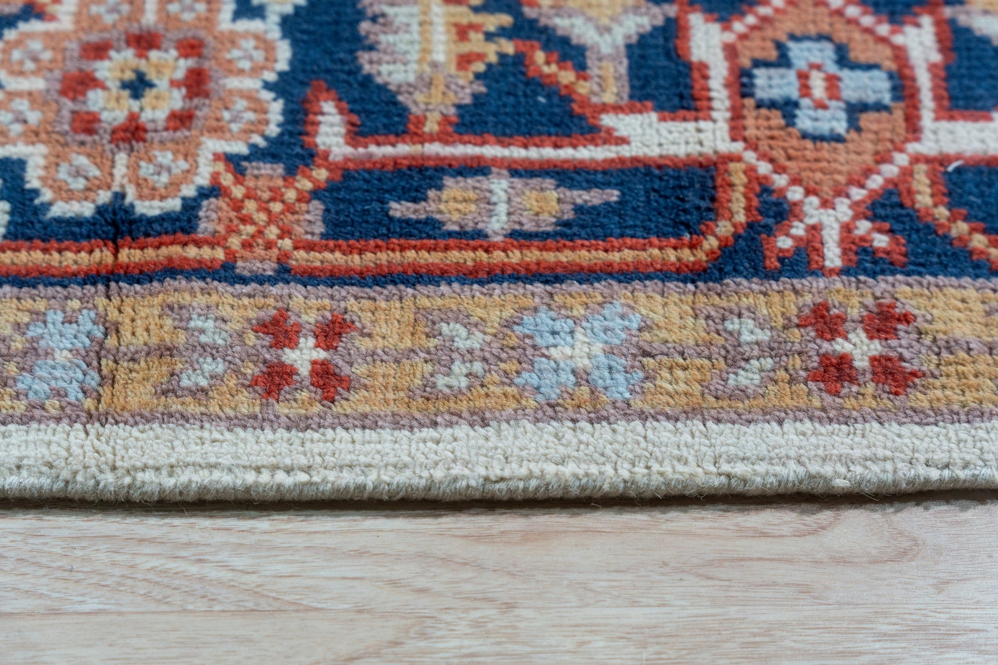 Classic Elegant Blue Hand-Knotted Wool Rug, showcasing intricate floral patterns in shades of blue and cream, lays elegantly on a light hardwood floor, radiating warmth and timeless sophistication in a well-lit interior space.