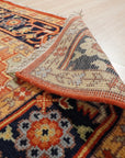 Harlow Oriental Rust Hand Knotted Wool Rug graces a warmly lit room, its intricate design and rich rust hues anchoring the space with traditional elegance. The hand-knotted wool construction is subtly highlighted, lending a sense of luxurious texture.