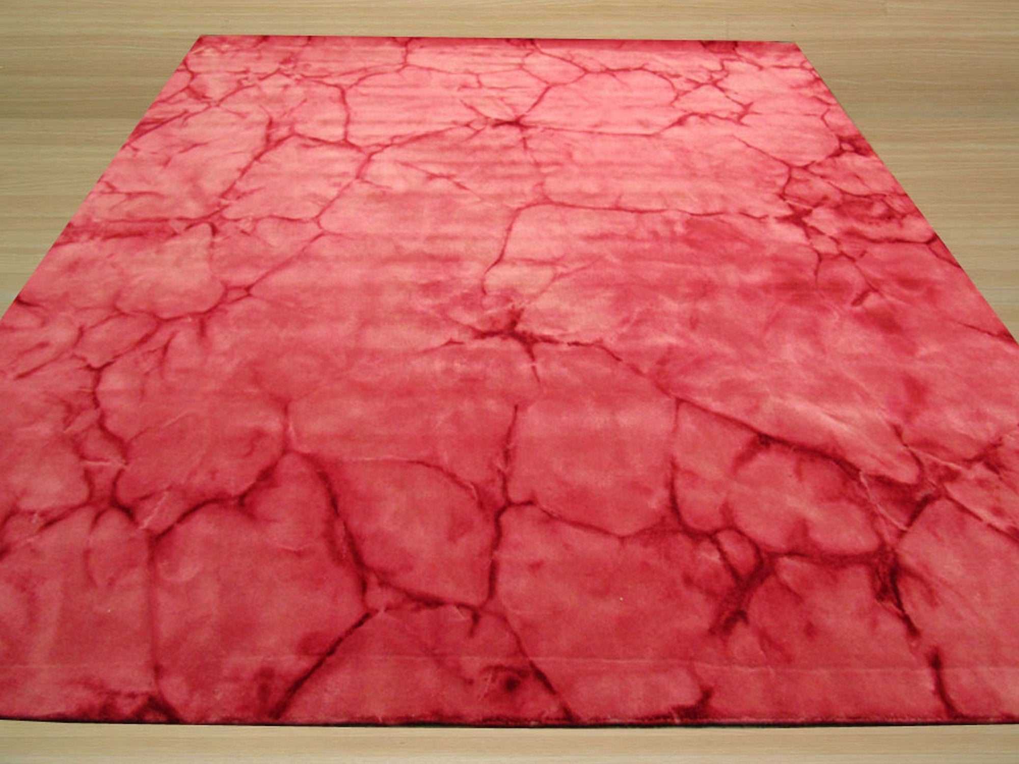 Sarrah Giselle Pink Hand Knotted Wool Rug, blending soft pink hues in a hand-knotted construction, lies flat on a light hardwood floor, showcasing its intricate geometric design and plush wool texture.