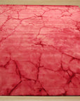 Sarrah Giselle Pink Hand Knotted Wool Rug, blending soft pink hues in a hand-knotted construction, lies flat on a light hardwood floor, showcasing its intricate geometric design and plush wool texture.